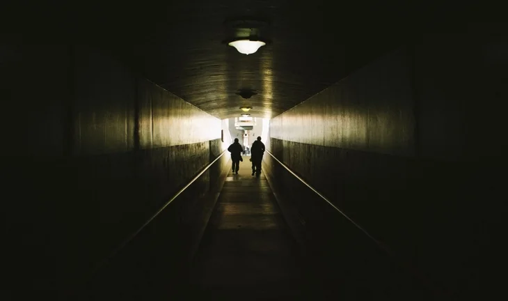 two figures running down a dark tunnel