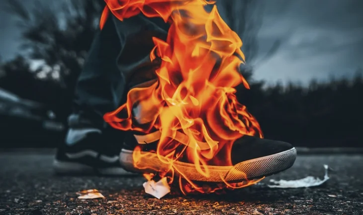 someone in trainers standing on burning paper, flames